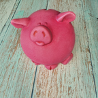 Pink pig-shaped object on a wooden surface