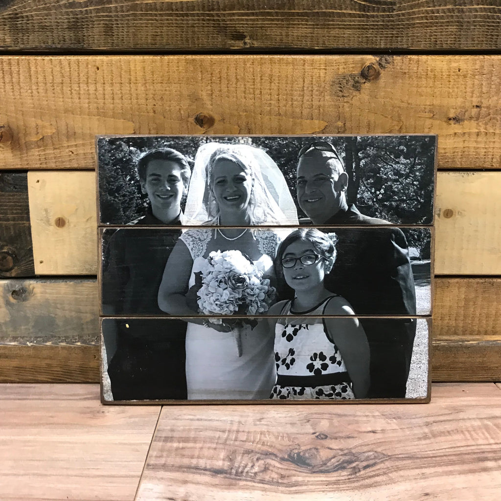 Black and white wedding family photo of a bride, groom and two children on a wood photo pallet