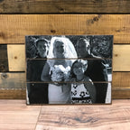 Black and white wedding family photo of a bride, groom and two children on a wood photo pallet