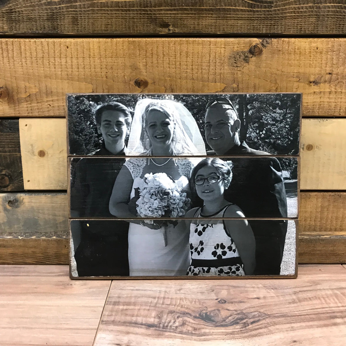 Black and white wedding family photo of a bride, groom and two children on a wood photo pallet