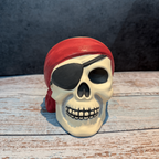 Pirate skull figurine with a red bandana on a wooden surface