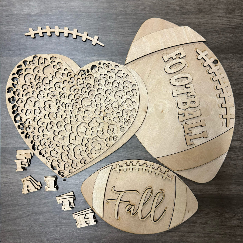Wooden cutouts shaped like a heart, footballs, and letters on a wooden surface