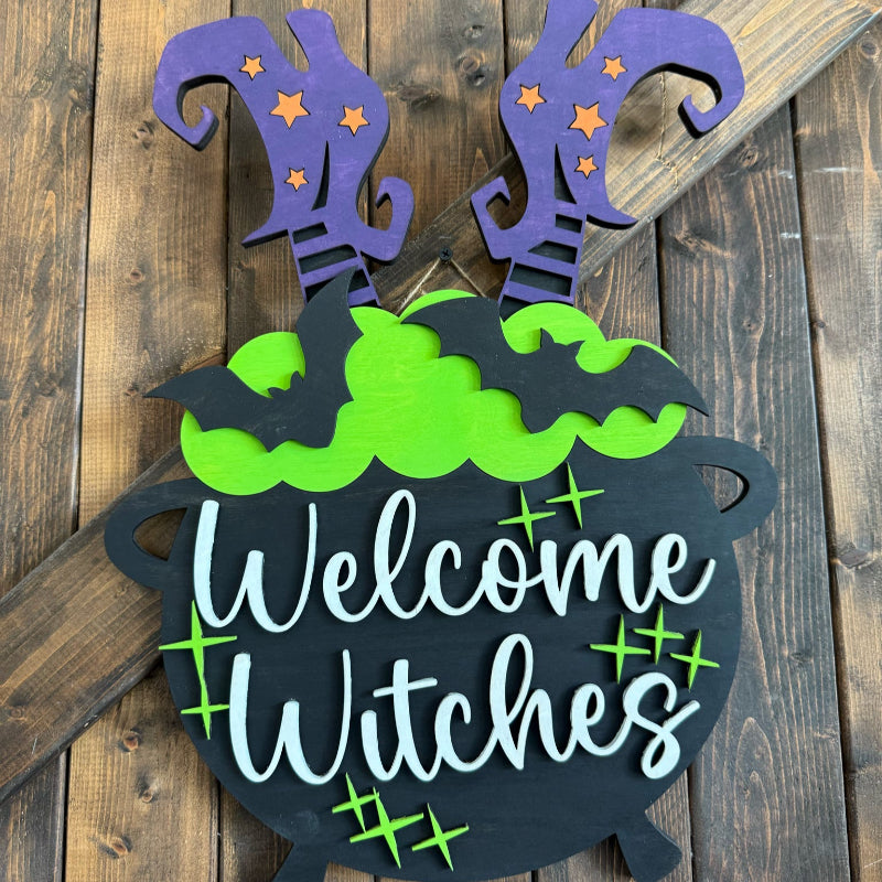 Decorative Halloween sign with 'Welcome Witches' text on a wooden background