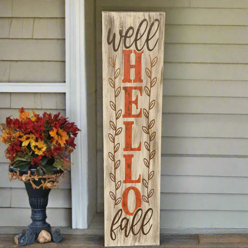 Wooden sign with 'Well HELLO fall' text on a porch with a floral arrangement.